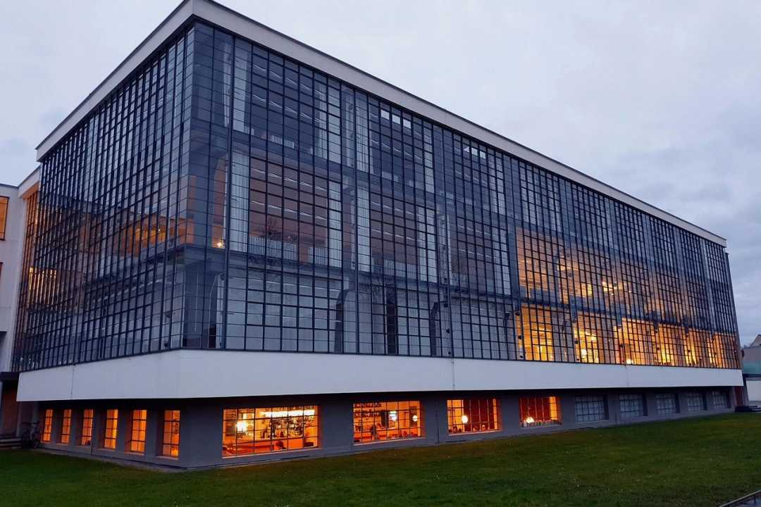 Bauhausgebäude Dessau mit beleuchteter Glasfassade am Abend