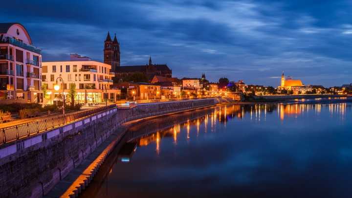Magdeburg an der Elbe bei Abenddämmerung mit beleuchteter Uferpromenade und Dom