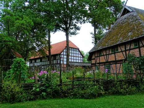 Fachwerkhäuser mit Reet- und Ziegeldach im Freilichtmuseum Diesdorf, umgeben von Bauerngarten und Holzzaun