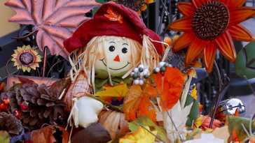 Strohpuppe umgeben von Herbstlaub